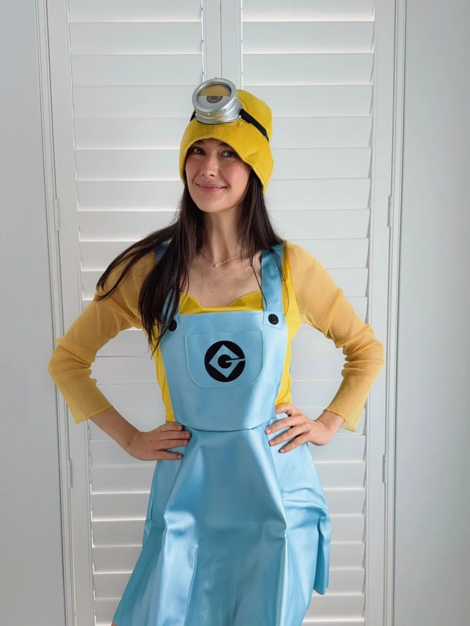 Minion party entertainer in yellow beanie with goggles and blue overalls posing in front of white shutters for a Melbourne Minions themed kids birthday party